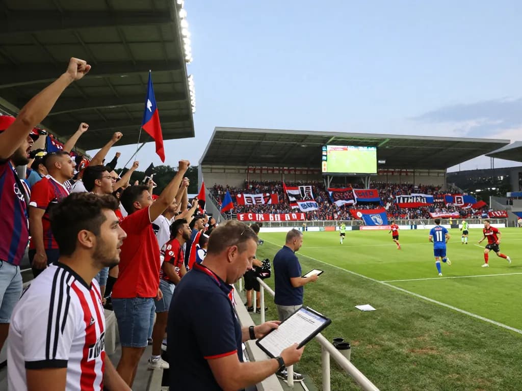Fan engagement and excitement during a football match while checking ผลบอล updates in the stadium.